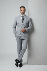 Man wearing light grey double-breasted suit with peak lapels and tailored fit.